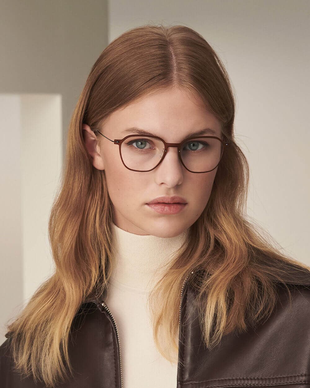 frau mit brauner lindberg korrektionsbrille und brauner lederjacke blickt in die kamera